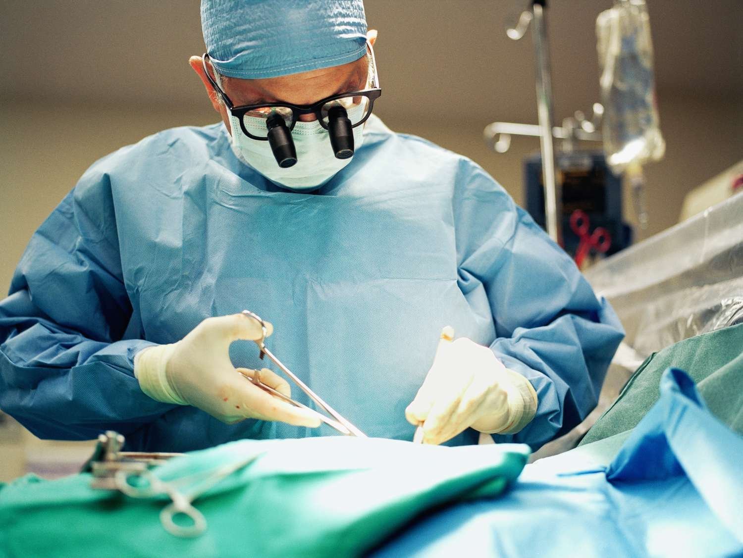 Surgeon performing an operation in a sterile operating room while wearing magnifying loupes and surgical attire